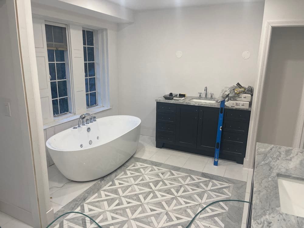 Modern bathroom featuring a freestanding tub, dark cabinetry, and elegant tile flooring.